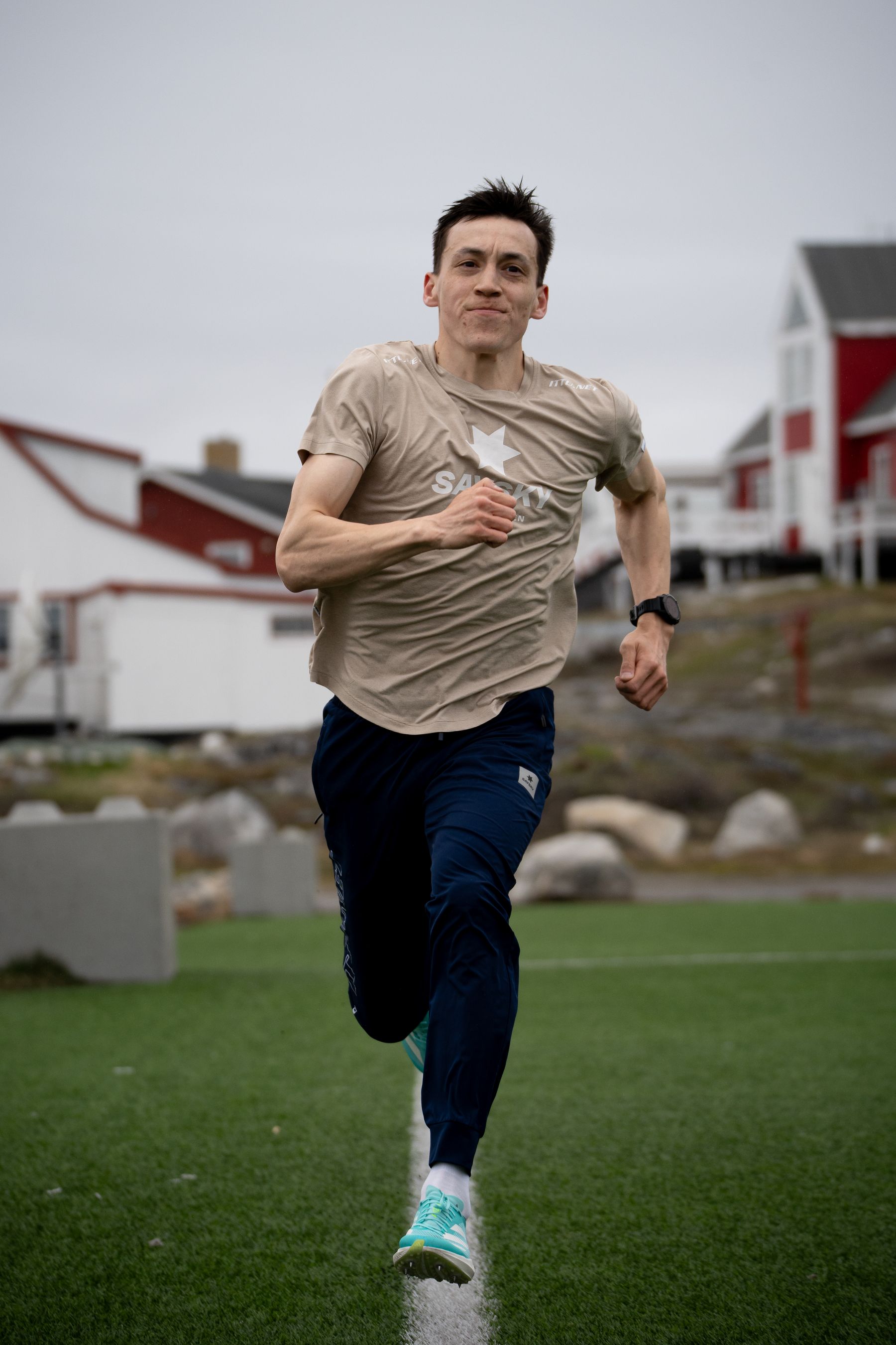 Løber på en bane med røde huse i Nuuk bagved