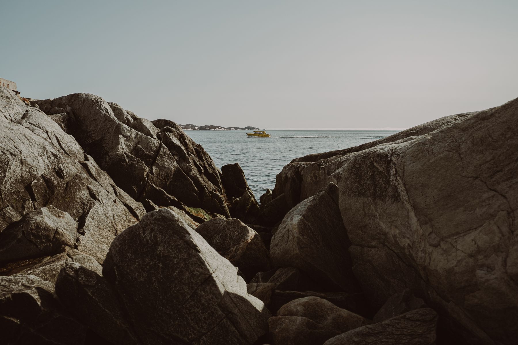 Gul båd mellem klipper på kysten ved Nuuk