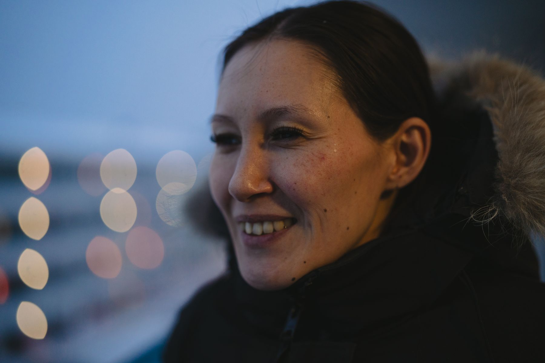 Kvinde i vinterjakke smiler i blå time