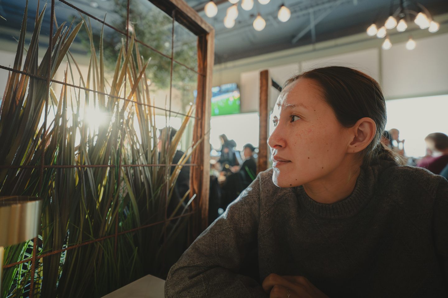 Kvinde sidder i en café og kigger ud i lyset